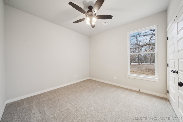 spare room featuring a ceiling fan, light colored carpet, visible vents, and baseboards