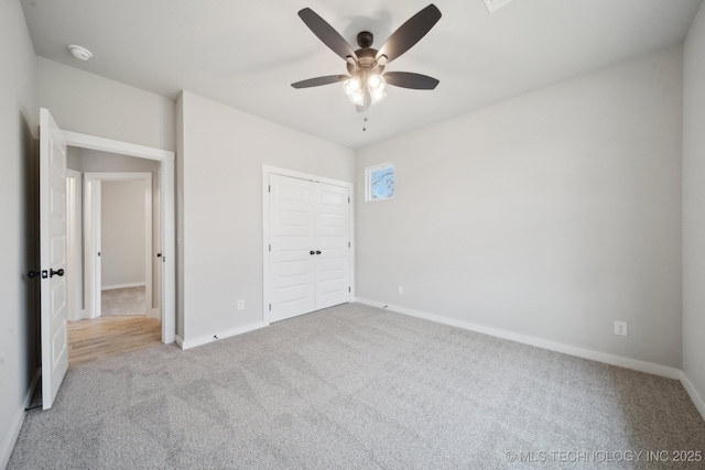 unfurnished bedroom featuring carpet floors, a closet, baseboards, and a ceiling fan