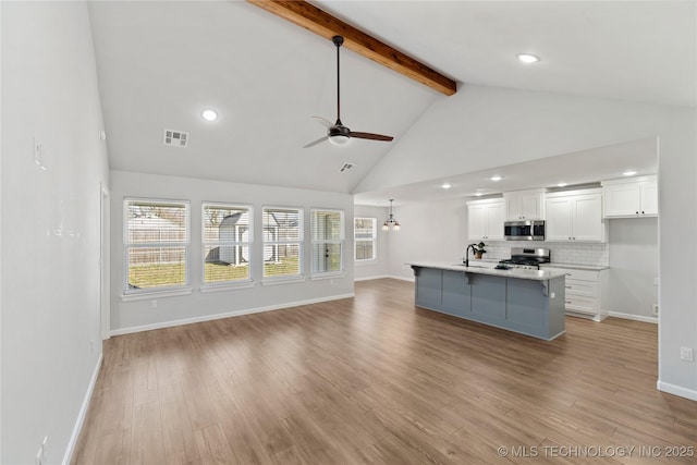 unfurnished living room with visible vents, light wood-style flooring, ceiling fan, high vaulted ceiling, and beamed ceiling