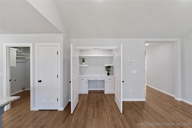 interior space with baseboards, vaulted ceiling, and wood finished floors