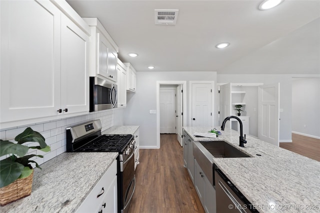 kitchen with visible vents, light stone counters, a sink, stainless steel appliances, and backsplash