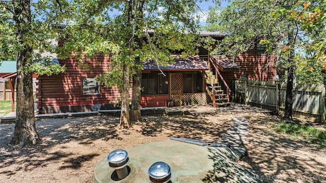 back of house with log exterior, a sunroom, fence, and stairway