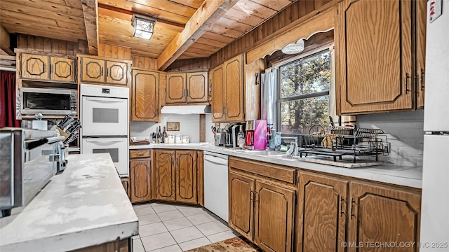 kitchen featuring light tile patterned floors, light countertops, wooden ceiling, white appliances, and beamed ceiling