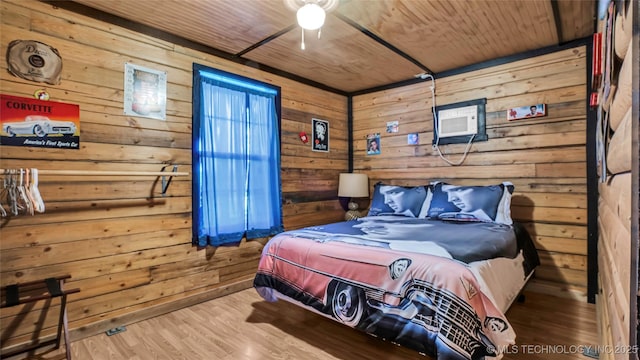 bedroom with an AC wall unit, wooden ceiling, wood finished floors, and wooden walls