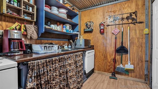 bar featuring a sink, wooden walls, dishwasher, and wood finished floors