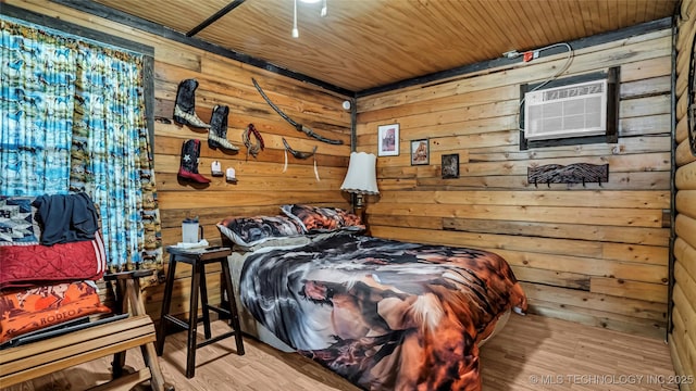 bedroom with wood walls, a wall unit AC, wood finished floors, and wooden ceiling