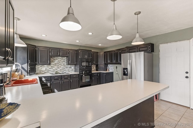 kitchen featuring decorative backsplash, light countertops, a sink, black appliances, and decorative light fixtures