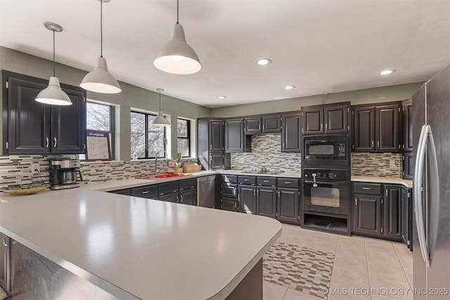 kitchen featuring a peninsula, decorative backsplash, a sink, and black appliances