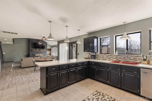 kitchen featuring a sink, dark cabinetry, light countertops, stainless steel dishwasher, and visible vents