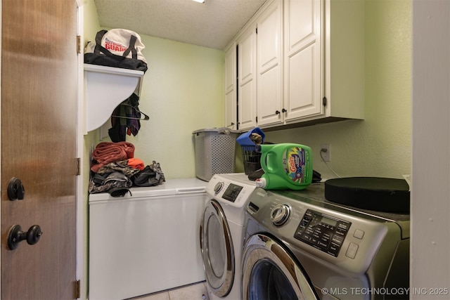 washroom featuring washer and clothes dryer, cabinet space, a textured ceiling, and light tile patterned floors