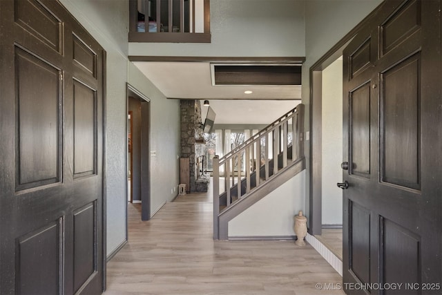 entrance foyer with baseboards, stairway, and light wood-style floors