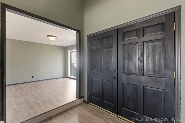 foyer entrance with baseboards and wood finished floors