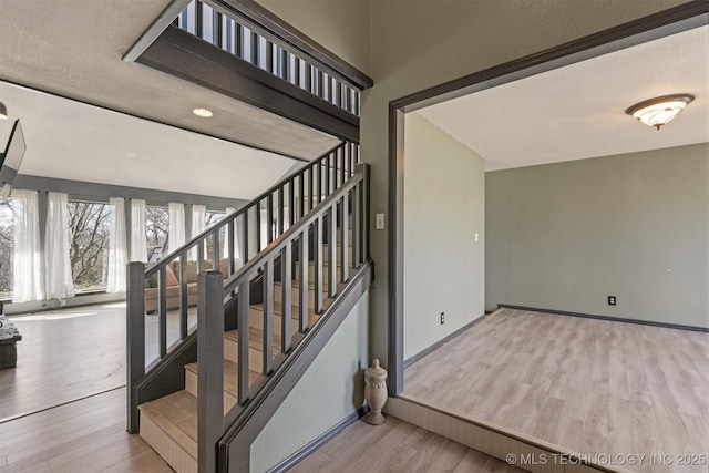 staircase with baseboards and wood finished floors
