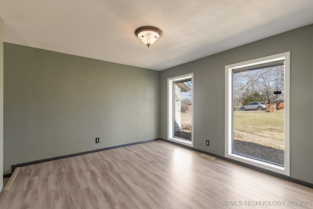 spare room featuring a textured ceiling, baseboards, and wood finished floors