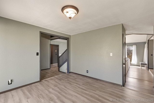 unfurnished room with stairway, baseboards, and light wood finished floors