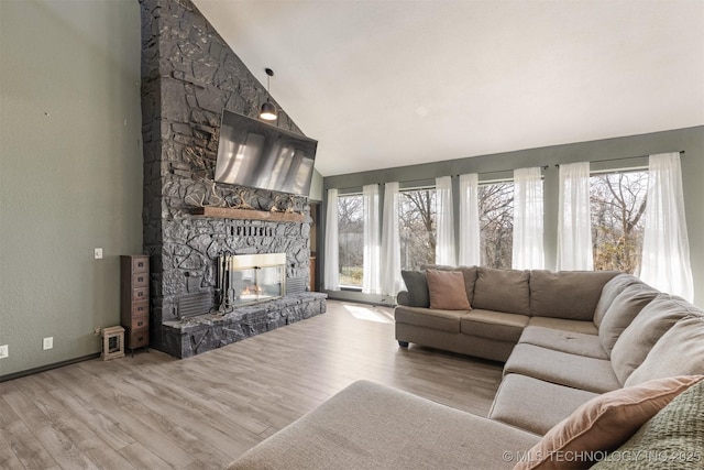 living room with plenty of natural light, a stone fireplace, and wood finished floors