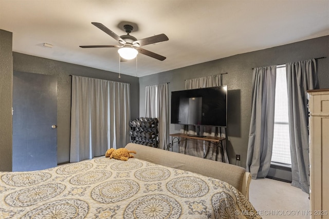 bedroom with carpet floors, a ceiling fan, a textured wall, and multiple windows