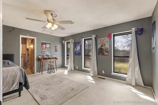 carpeted bedroom with baseboards, ceiling fan, visible vents, and ensuite bathroom