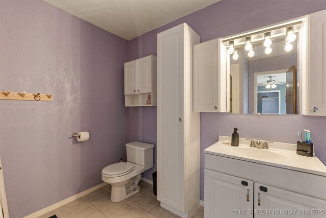 bathroom with ceiling fan, tile patterned floors, baseboards, vanity, and toilet