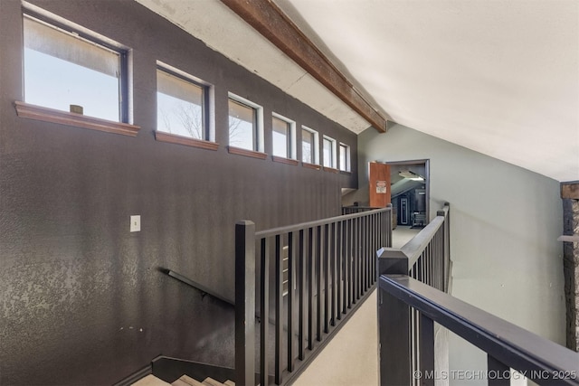 stairway featuring plenty of natural light and lofted ceiling with beams