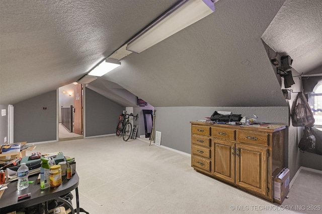 additional living space featuring baseboards, a textured ceiling, lofted ceiling, and light carpet