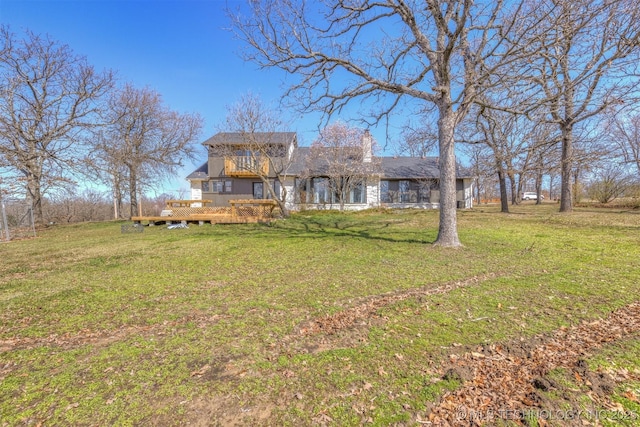 view of front facade featuring a deck, a chimney, and a front lawn