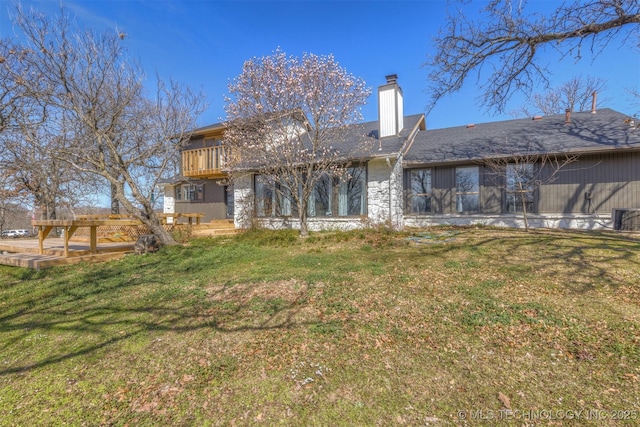 back of property featuring a balcony, a yard, and a chimney