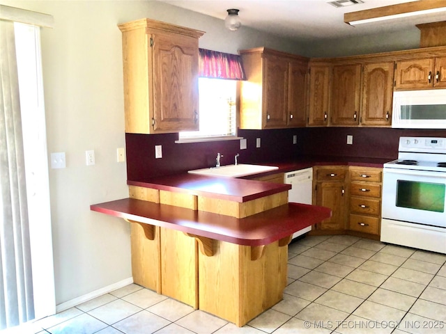 kitchen with white appliances, decorative backsplash, a peninsula, a sink, and light tile patterned flooring