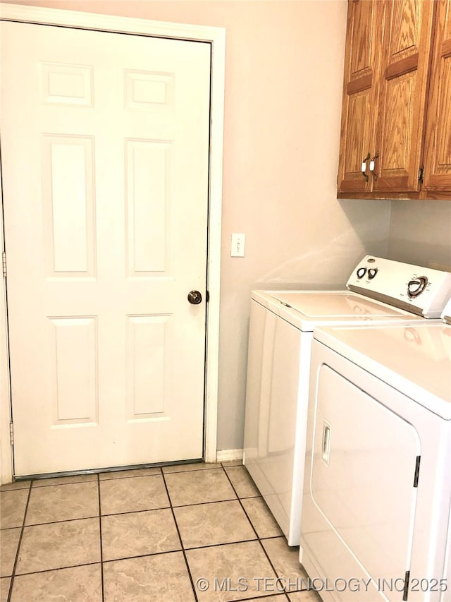 clothes washing area featuring cabinet space, washing machine and clothes dryer, and light tile patterned floors