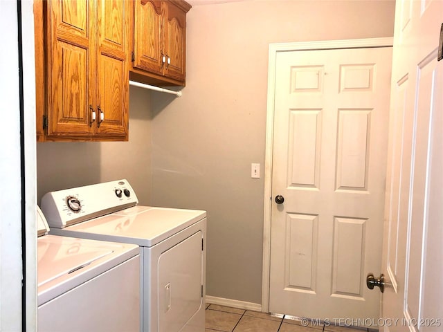 laundry room featuring cabinet space, washer and clothes dryer, baseboards, and light tile patterned flooring