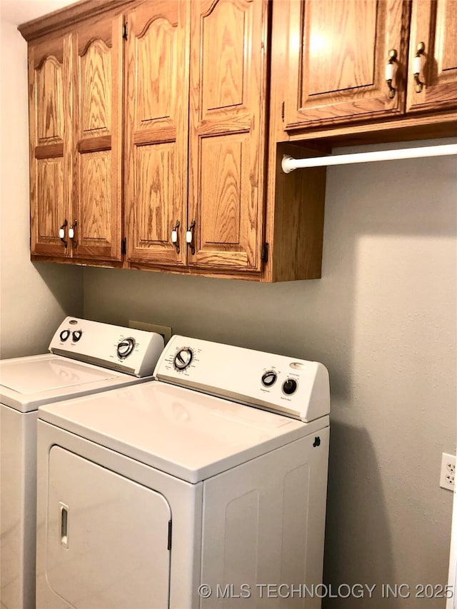 clothes washing area featuring washing machine and dryer and cabinet space