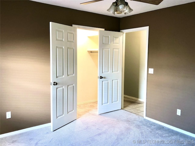 unfurnished bedroom with baseboards, a spacious closet, a closet, and light colored carpet