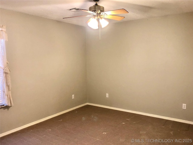 spare room featuring visible vents, dark carpet, a ceiling fan, and baseboards