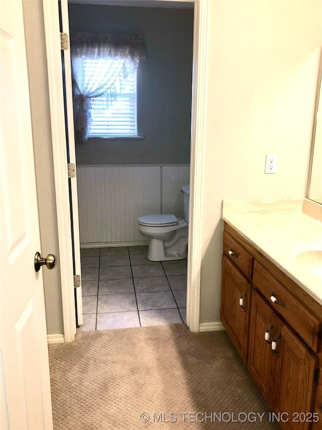 bathroom featuring toilet, wainscoting, vanity, and tile patterned floors