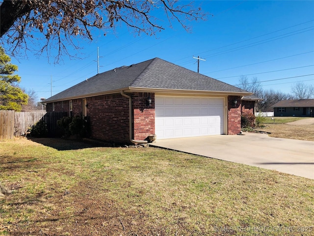 view of side of property with a garage, brick siding, fence, and a lawn