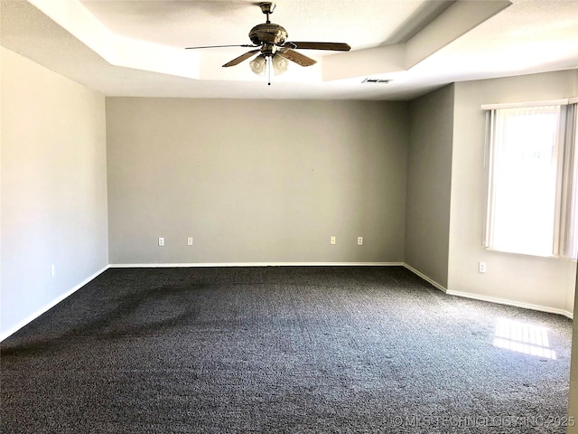 unfurnished room featuring a tray ceiling, carpet, and baseboards