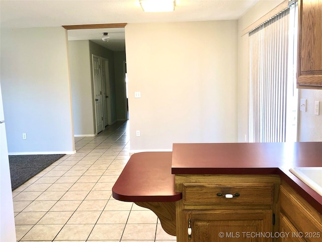 unfurnished dining area with light tile patterned floors and baseboards