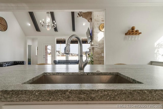 kitchen with vaulted ceiling with beams, a chandelier, a sink, and decorative light fixtures