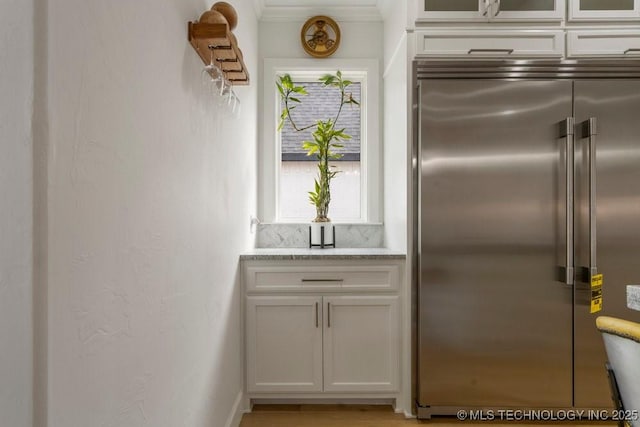 kitchen featuring white cabinetry, plenty of natural light, glass insert cabinets, and stainless steel built in refrigerator