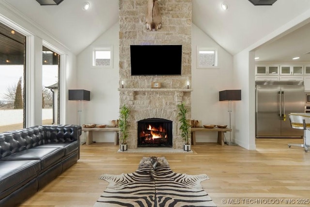 living area featuring light wood-style floors, recessed lighting, a large fireplace, and high vaulted ceiling