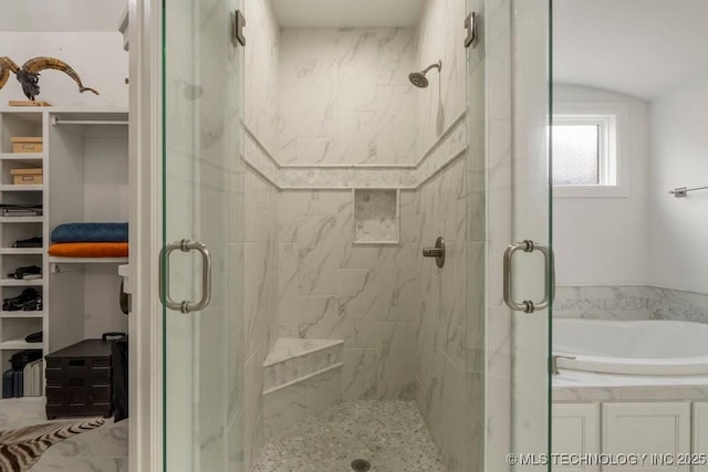 bathroom with a stall shower, a walk in closet, and a garden tub