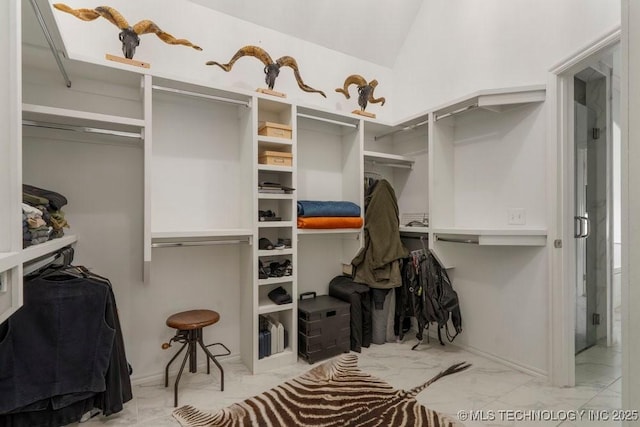 walk in closet with marble finish floor and vaulted ceiling