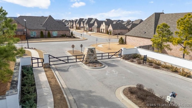 view of road with a gate, sidewalks, a gated entry, a residential view, and curbs