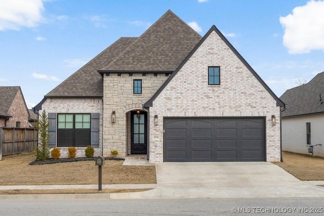 french country inspired facade featuring driveway, a shingled roof, fence, and brick siding