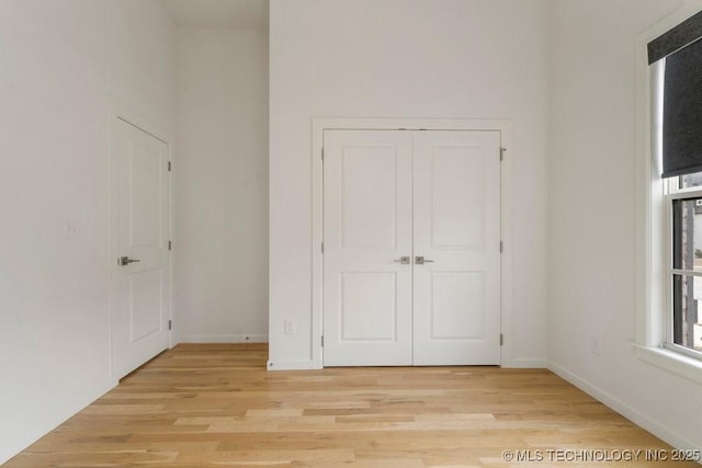 unfurnished bedroom with a closet, light wood-style flooring, and baseboards