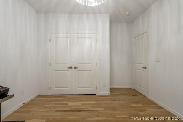 unfurnished bedroom featuring a closet, light wood-style flooring, and baseboards