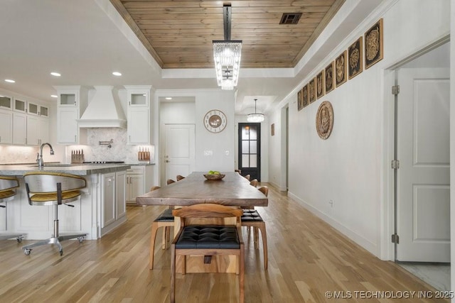 dining area featuring visible vents, wooden ceiling, a tray ceiling, crown molding, and light wood-type flooring