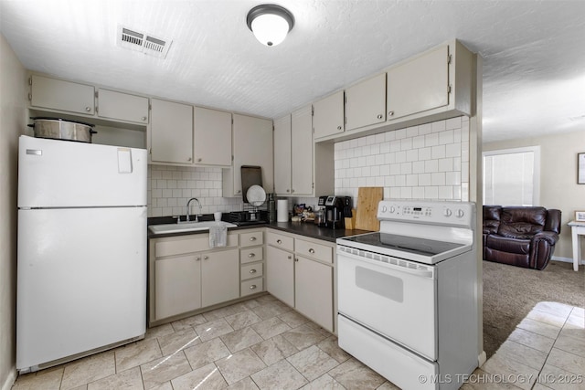 kitchen featuring a textured ceiling, white appliances, a sink, visible vents, and decorative backsplash