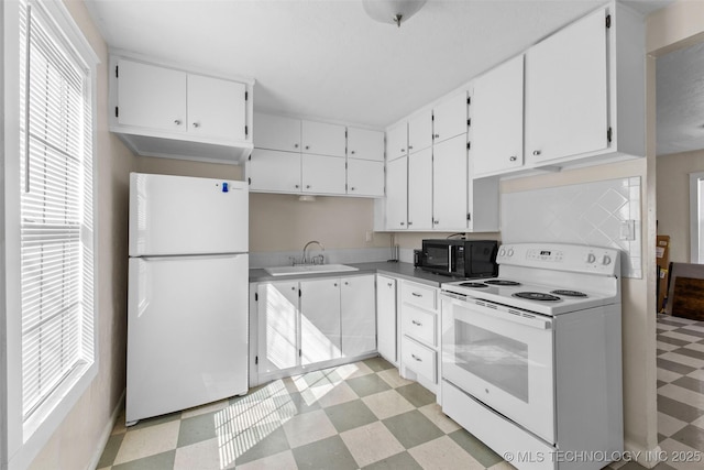 kitchen featuring white appliances, a sink, white cabinetry, light countertops, and light floors