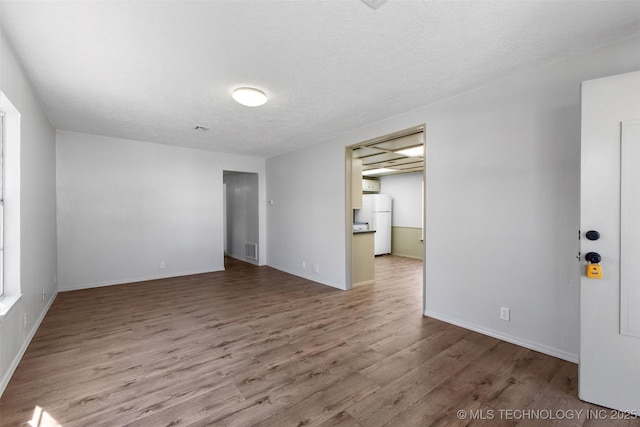 spare room with a textured ceiling, wood finished floors, and visible vents